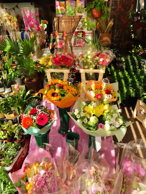 A vibrant floral display featuring a variety of fresh flower bouquets arranged on a pink table surface at Florist Upper Norwood. The display includes bouquets wrapped in bright yellow, white, and pink